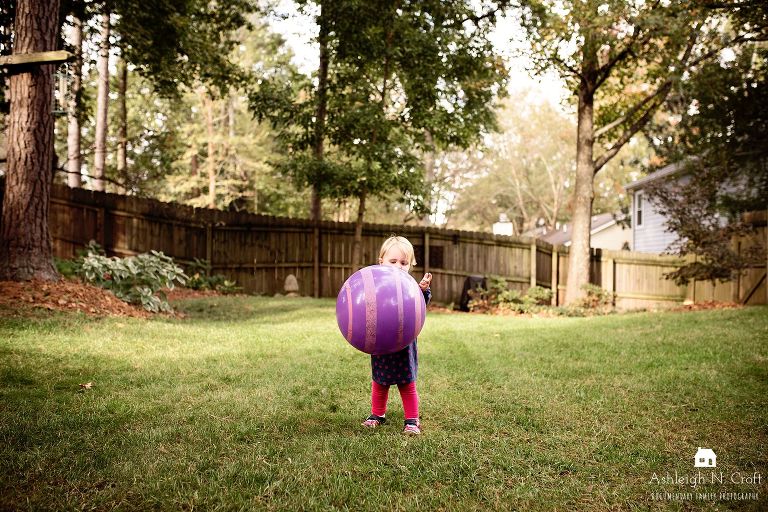 girl throwing ball in backyard